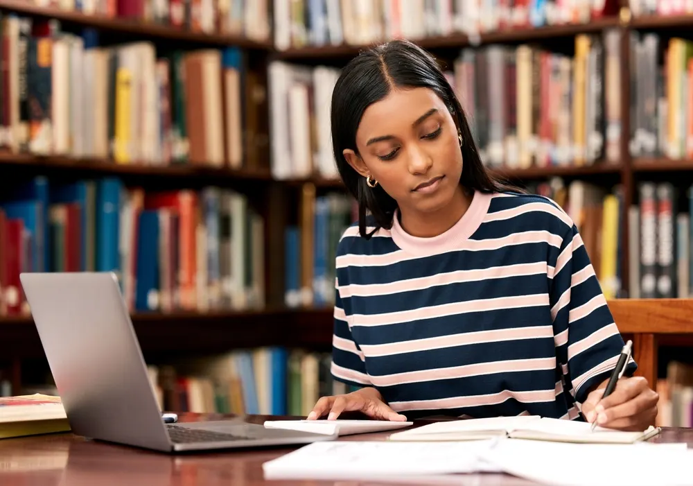 College student studying with a laptop and notes